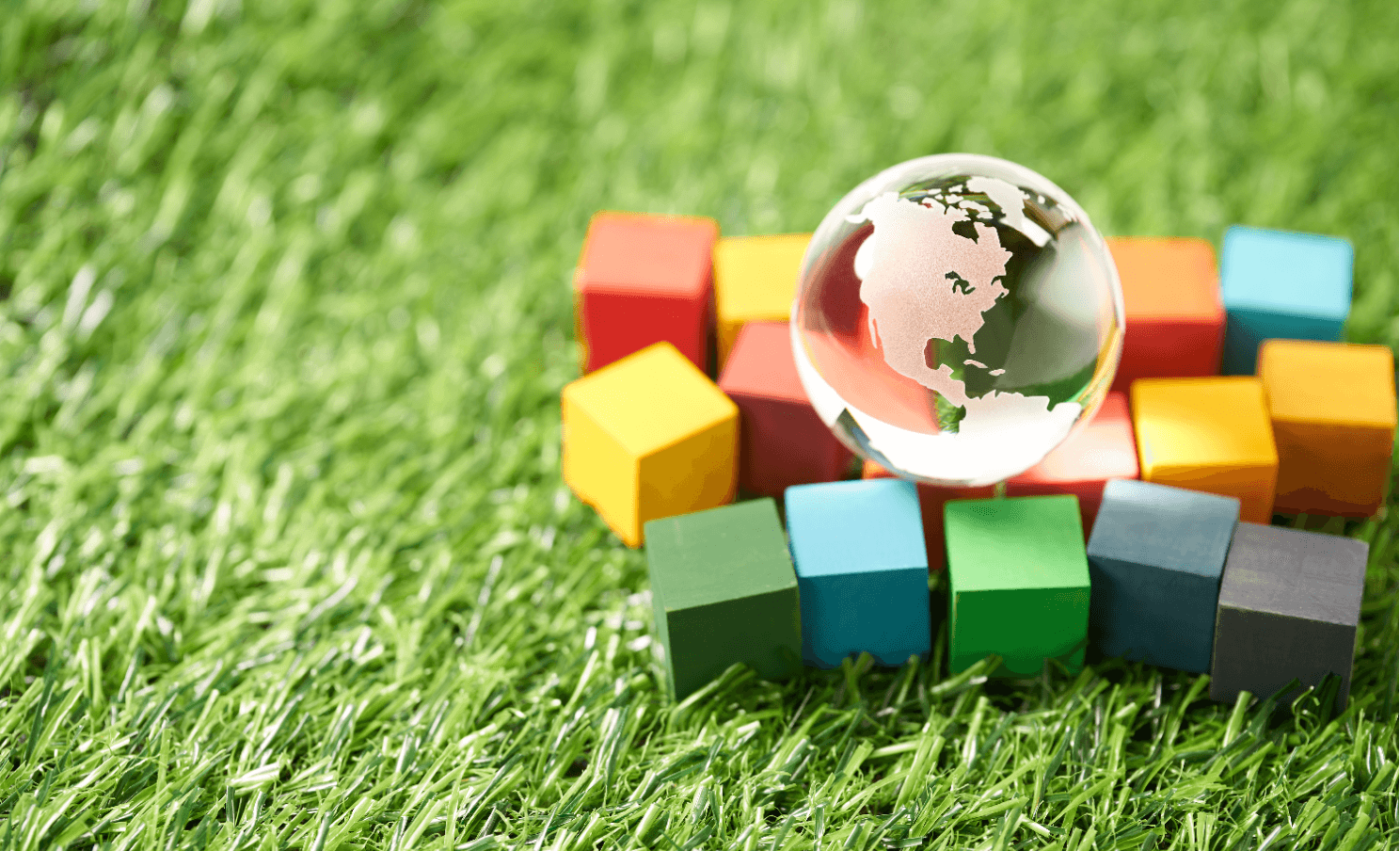 Globe du monde avec des cubes sur de l'herbe Visuel utilisé pour illustré le baromète RSE de Kantar Media