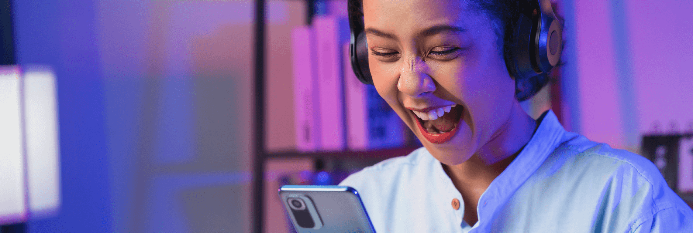 Une jeune femme sourit devant son téléphone, pour illustrer les tendances pub 2024 sur Facebook et Instagram selon Kantar Media