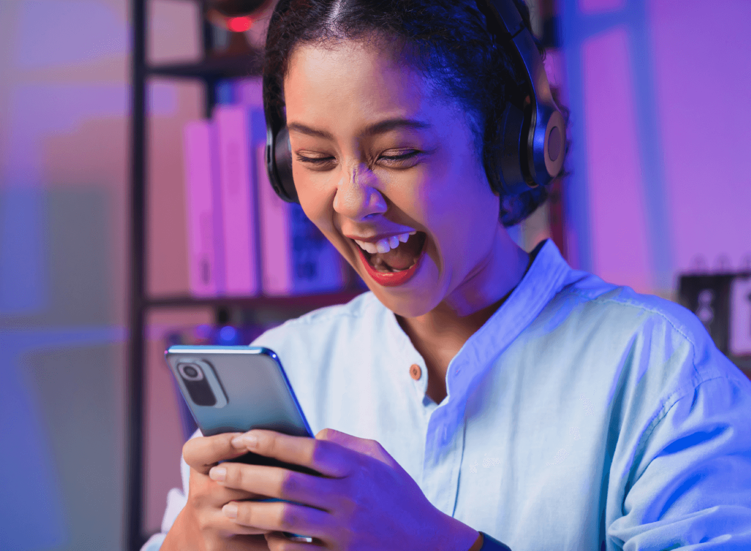 Une jeune femme sourit devant son téléphone, pour illustrer les tendances pub 2024 sur Facebook et Instagram selon Kantar Media
